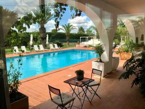 加拉托内坎皮拉提尼农家公寓式酒店的游泳池前设有桌椅