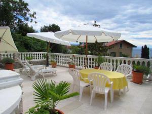 奥帕提亚Guesthouse Katarina的庭院配有桌椅和遮阳伞。