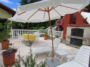 奥帕提亚Guesthouse Katarina的庭院配有桌椅和遮阳伞。