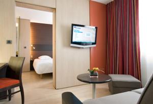 布格奈斯Hôtel Oceania Nantes Aéroport的酒店客房设有一张床和墙上的电视