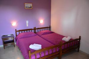 阿吉亚玛丽娜Voula Apartments的一间卧室配有一张带紫色床单的木床