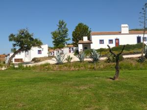 米尔芳提斯城Monte Do Adail Turismo Rural Casa De Campo的白色的房子,有绿树的院子
