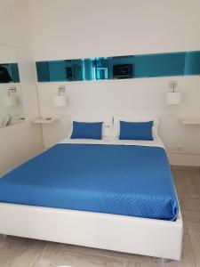 切萨雷奥港Di Ma B&B的客房内的白色床和蓝色枕头