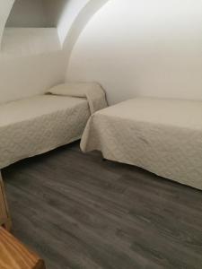 切里尼奥拉Maison Josephine的小型客房铺有木地板,配有两张床。