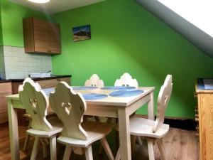 克鲁斯兹考采Apartamenty "U Bańki"的厨房设有一张桌子和椅子,拥有绿色的墙壁