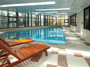 北京北京华腾美居酒店的大楼内一个带长凳的大型游泳池