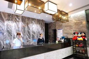上海麦新格精品酒店川沙店的两名妇女站在酒店大堂的柜台
