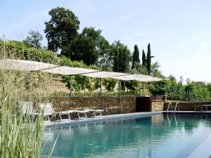 皮内罗洛Residenza la beccata的一个带遮阳伞和椅子的游泳池,位于墙上