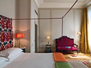 佛罗伦萨安缇卡托瑞迪维亚托尔纳布奥尼酒店的一间卧室配有一张床和一张红色椅子