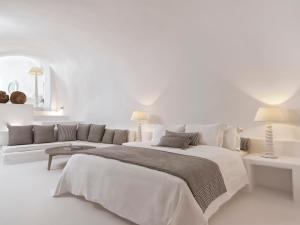 易莫洛林Katikies Chromata Santorini - The Leading Hotels of the World的白色卧室设有一张大床和一张沙发