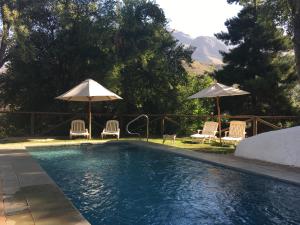 圣阿方索Cabañas Valle de Montañas的一个带两把椅子和遮阳伞的游泳池