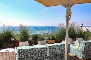 特拉维夫梅洛迪酒店-阿特拉斯精品酒店的一个带两张沙发和一把遮阳伞的庭院和大海