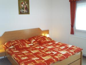 佐洛卡罗斯Andrea Apartmanok的一间卧室配有一张带红色棉被的床和窗户。
