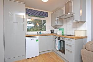 波斯陶恩Mount Hawke Holiday Bungalows的厨房配有白色橱柜和白色冰箱。