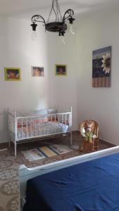 索尔索Casa Marina Lu Tuvaraggiu Casa vacanze的一间卧室配有一张婴儿床和一把椅子。