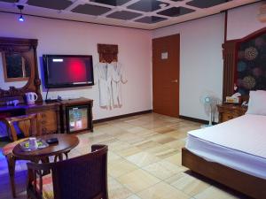 釜山普拉斯汽车旅馆的一间卧室配有一张床、一台电视和一张桌子