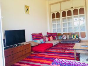 阿加迪尔CosyFlat 10minBeach的客厅配有红色沙发和平面电视