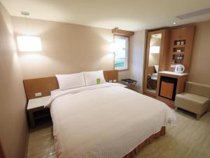 台南康桥商旅 - 台南赤崁楼馆的卧室配有一张白色大床和一把椅子