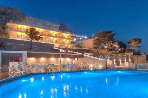 马苏里Carian Hotel的晚上在酒店前面的一个游泳池