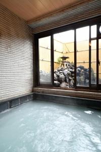 草津草津温泉旅馆的带窗户的客房内的热水浴池