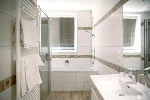维也纳玫瑰谷餐厅酒店的白色的浴室设有浴缸和水槽。