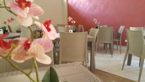 阿曼泰阿A'MANTIA HOTEL的用餐室配有桌椅和粉红色的鲜花