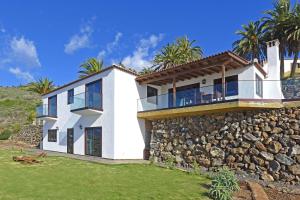 蒂哈拉费Villa Vista Mar的白色的房子,有石墙和棕榈树