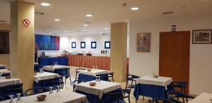 卡达克斯奥克塔维亚酒店的用餐室配有白色的桌子和蓝色的椅子