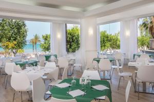 埃尔阿雷纳尔哇啦海滩酒店的餐厅设有白色的桌椅,享有海滩美景。