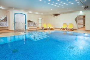 奥伯斯特多夫"Haus Berktold" - Annehmlichkeiten von 4-Sterne Familien-und Wellnesshotel Viktoria können mitbenutzt werden的一个带椅子的游泳池和一个游泳池的房间