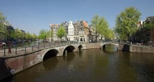 阿姆斯特丹阿姆斯特丹牛奶屋奢华住宿加早餐旅馆的一座建有建筑物的城市里河流上的桥梁