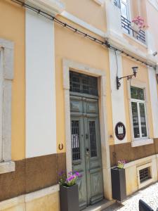 法鲁Guest House do Largo的一座带绿门和两扇窗户的建筑