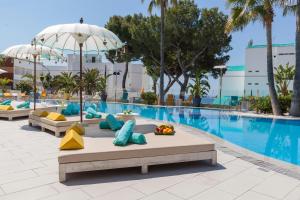 马盖鲁夫Sotavento Club Apartments - Adults Only的度假村的游泳池配有枕头和遮阳伞