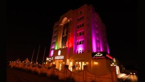 锡卜Remas Hotel Suites - Al Khoudh, Seeb, Muscat的一座粉红色和紫色的建筑