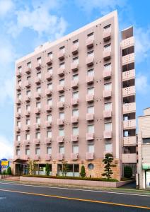 松山Super Hotel Matsuyama的街道边的粉红色建筑