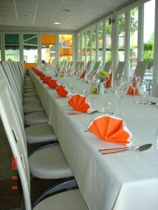 采列河卡霍特宾馆的一张长桌子,里面摆放着橙色餐巾和椅子