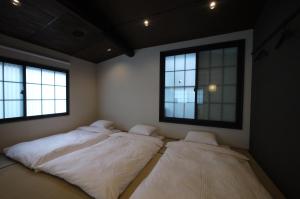 京都Machiya Kaemon的带2扇窗户的客房内的2张床