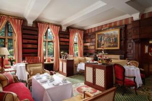 伦敦红色康乃馨肯辛顿里程碑酒店的图书馆内带桌椅的餐厅