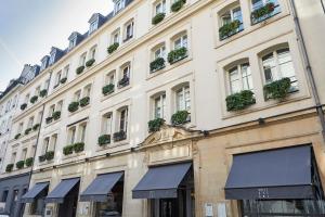 巴黎贝尔阿米酒店的一座白色的大建筑,窗户上布满了植物