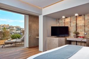雅典米康海峡18号酒店的一间卧室设有一张床、一台电视和一个阳台。