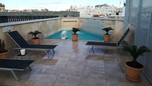 塞维利亚Apartamentos RG Suites Jardines de Murillo的一个带椅子的阳台和一个屋顶游泳池