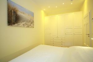 瓦尔内明德酷派欧亚瑟公寓的卧室配有一张床,墙上挂有绘画作品