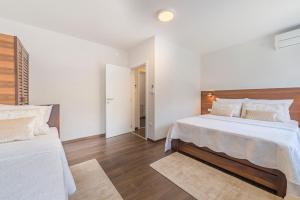 普利特维采湖Up27 Suites Plitvice的白色卧室设有两张床,铺有木地板