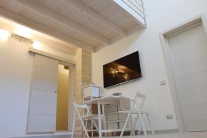 加拉蒂纳ArcoSalento的一间设有白色椅子和墙上电视的房间