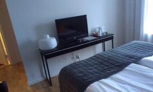 博里霍尔姆英格丽别墅酒店的一间卧室配有一张床和一张桌子上的电视