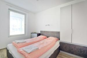 希欧福克Villa Oliver 3 Siófok的一间卧室配有一张带粉色床单的床和一扇窗户。