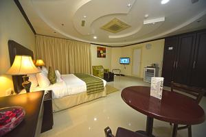 阿吉曼Alain Hotel Ajman的酒店客房配有一张床铺和一张桌子。