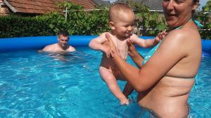 伦蒂Rózsa apartman的把婴儿抱在游泳池里的男人