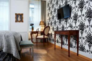 苏黎世市政厅精品酒店的一间卧室配有书桌,墙上配有电视