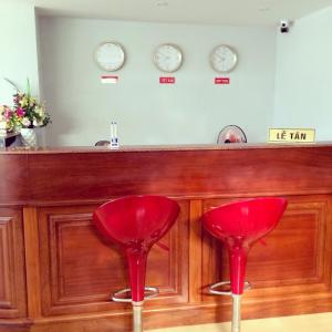 金瓯Khách sạn Phú An的酒吧前有两把红色椅子,有时钟